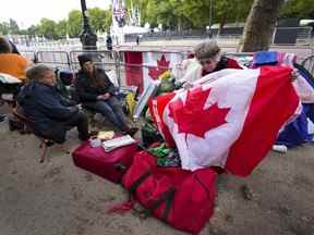 Bernadette Christie, de Grand Prairie, en Alberta, cherche une épinglette canadienne sur un drapeau aux portes du palais de Buckingham à Londres, le vendredi 16 septembre 2022.