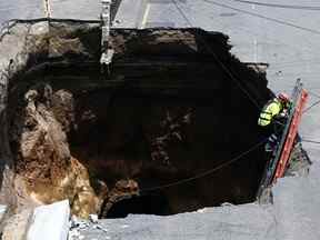 Un sauveteur descend une échelle dans un trou géant dans une route, à Villa Nueva, le 25 septembre 2022.