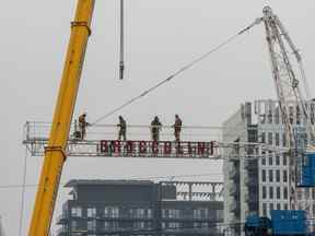 Des travailleurs de la construction assemblent une grue dans les airs à Toronto.
