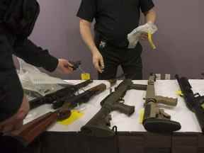 Des agents de la Police provinciale de l'Ontario se préparent à empocher une arme à feu après que la Police provinciale de l'Ontario a organisé une conférence de presse à Vaughan, en Ontario, le jeudi 23 février 2017.