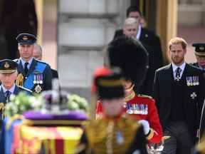 Le roi Charles III, le prince William, prince de Galles et le prince Harry, duc de Sussex marchent derrière le chariot à canon portant le cercueil de feu la reine Elizabeth II alors qu'il quitte le palais de Buckingham, transférant le cercueil au palais de Westminster, à Londres, mercredi , 14 septembre 2022.