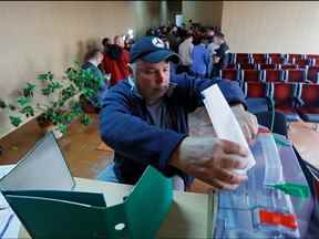 Un homme vote lors d'un référendum sur la sécession de la région de Zaporizhzhia de l'Ukraine et son adhésion à la Russie, dans la ville sous contrôle russe de Melitopol dans la région de Zaporizhzhia, Ukraine, le 26 septembre 2022.