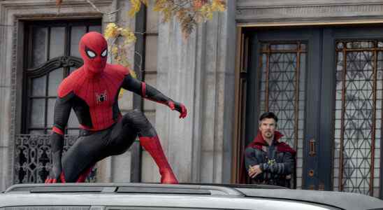 Spider-Man crouches on top of a car while Dr. Strange looks on with his arms crossed