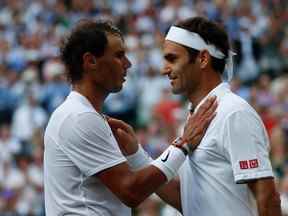 Dans cette photo d'archive prise le 12 juillet 2019, le Suisse Roger Federer (R) s'entretient avec l'Espagnol Rafael Nadal (L) après que Federer a remporté la demi-finale du simple messieurs le jour 11 des championnats de Wimbledon 2019 au All England Lawn Tennis Club à Wimbledon, au sud-ouest de Londres.