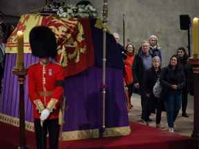 Des membres du public défilent devant le cercueil drapé du drapeau de la reine Elizabeth II posé en l'état sur le catafalque alors qu'ils entrent dans Westminster Hall au milieu de la nuit le 17 septembre 2022 à Londres.