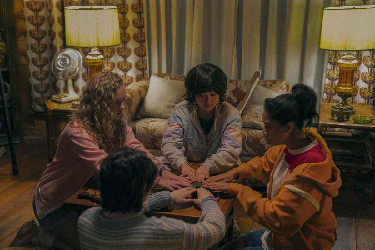 Quatre filles assises autour d'une table dans un salon, les mains posées sur une planche à ouji.