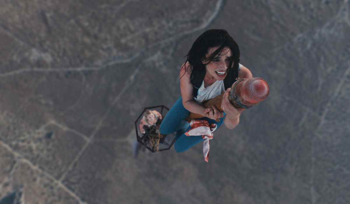 Une femme visiblement affligée alors qu'elle grimpe au sommet d'une tour radio dans un désert.