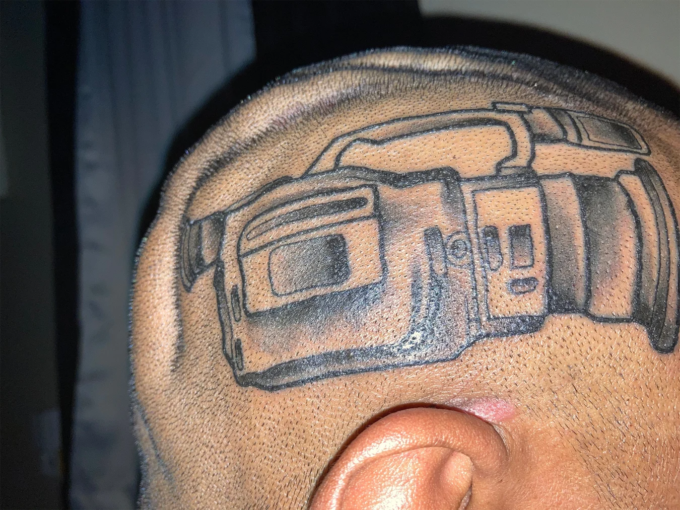 Un homme avec un tatouage de la caméra vidéo Sony VX1000 sur la tête.