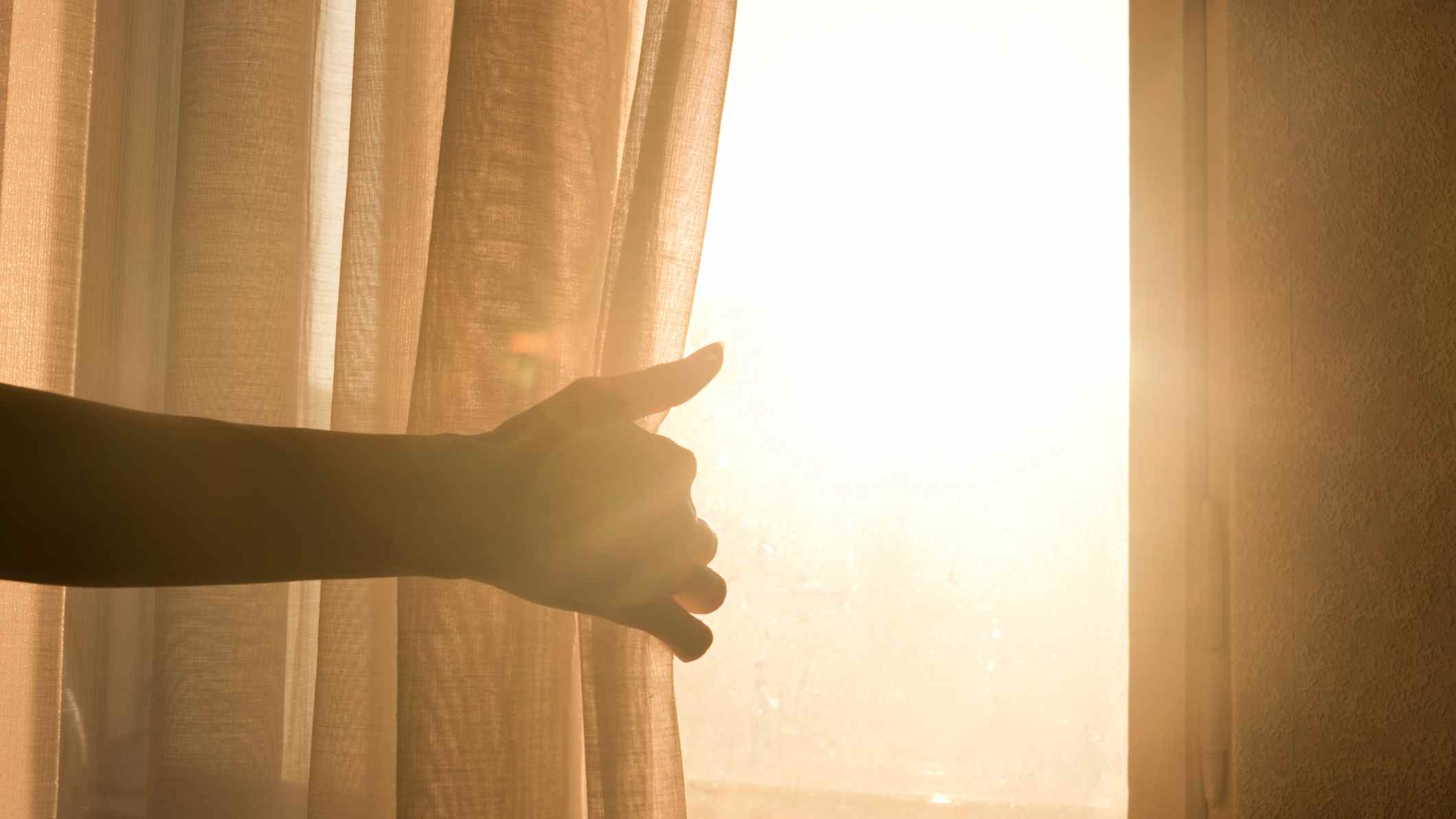 Un homme ouvre les rideaux par une belle matinée ensoleillée