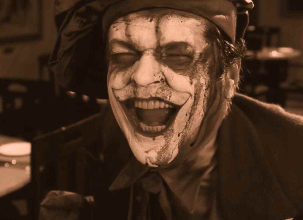Jack Nicholson dans le rôle du Joker hurlant de rire alors que son maquillage se décolle pour révéler sa peau blanche décolorée dans Batman : The Silent Motion Picture.