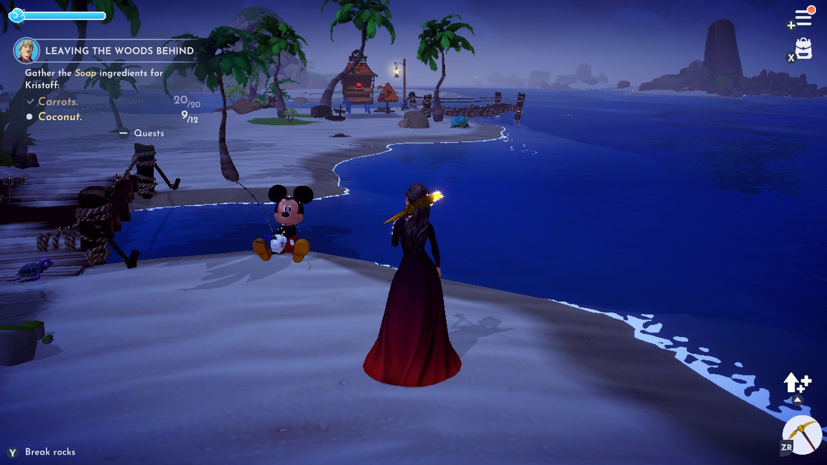 Mickey Mouse pêchant sur une plage, sauf qu'il fait face au sable.  une silhouette vêtue d'une longue robe rouge se tient au-dessus de lui