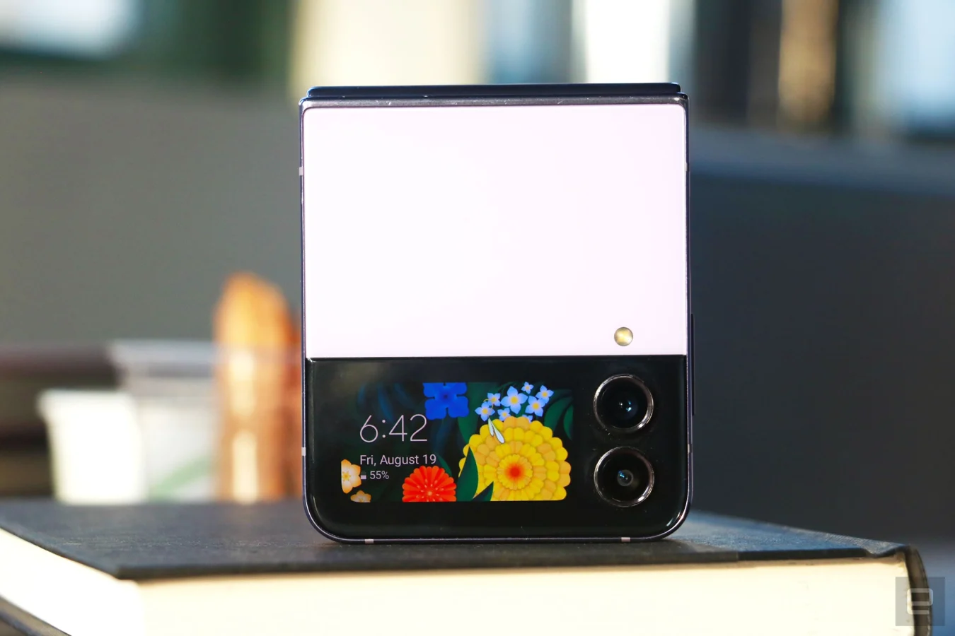 Le Galaxy Z Flip 4 fermé et soutenu le long de son bord supérieur avec son écran de couverture et ses caméras externes vers l'extérieur.