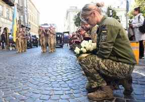 Des soldats ukrainiens s'agenouillent tandis que les cercueils de Roman Vyshynskyi, Yuriy Lelyavskyi et Ihor Hadyak – trois soldats tués en combattant les Russes – sont transportés lors d'une cérémonie funéraire vendredi à Lviv.