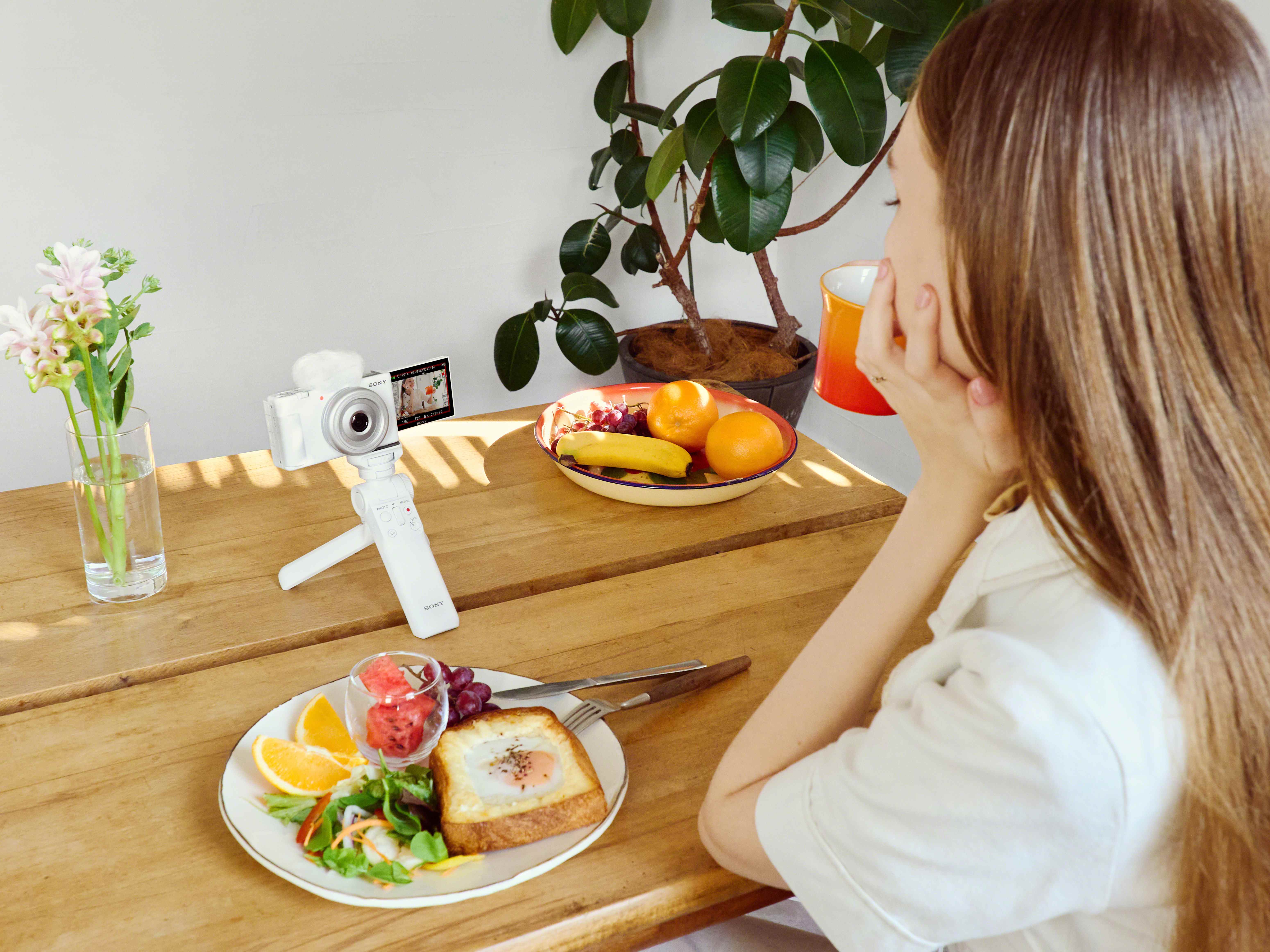 Une personne vlogging avec le Sony ZV-1F placé sur une table entourée de nourriture