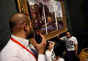 Des militants du groupe de campagne 'Just Stop Oil', les mains collées au cadre de la peinture 'The Hay Wain' de l'artiste anglais John Constable, mais couverts dans une fausse version 'non datée' comprenant des routes et des avions, protestent contre l'utilisation de combustibles fossiles, à la National Gallery de Londres le 4 juillet 2022.