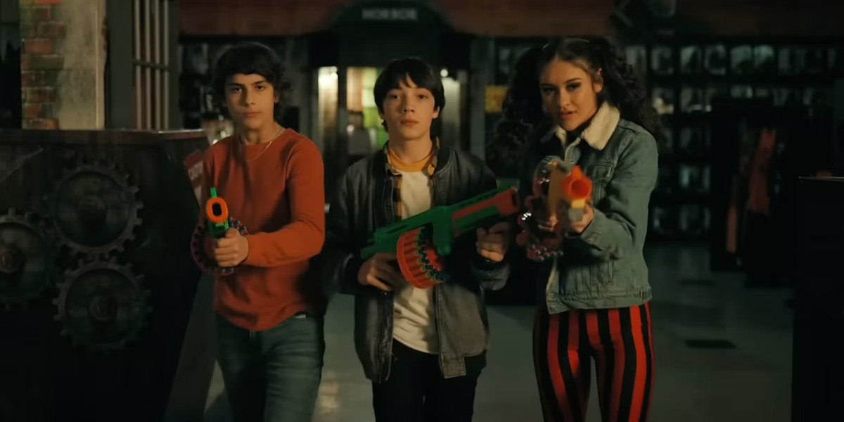 Trois adolescents avec des fusils à pompe marchent vers la caméra dans Spirit Halloween.
