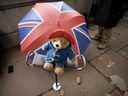 Un ours en peluche Paddington est placé sur une chaise à côté d'un parapluie du drapeau de l'Union alors que les gens attendent en face du palais de Westminster pour être les premiers à faire leurs adieux à la reine Elizabeth II à Londres le 14 septembre 2022.