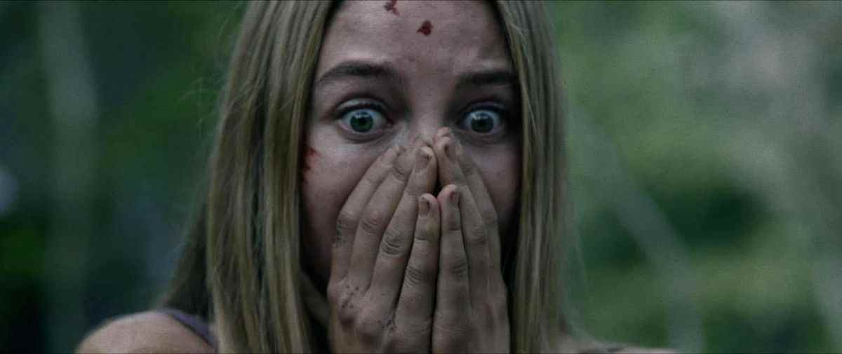 Une femme blonde avec du sang sur son visage serre ses mains sur sa bouche dans Wrong Turn.