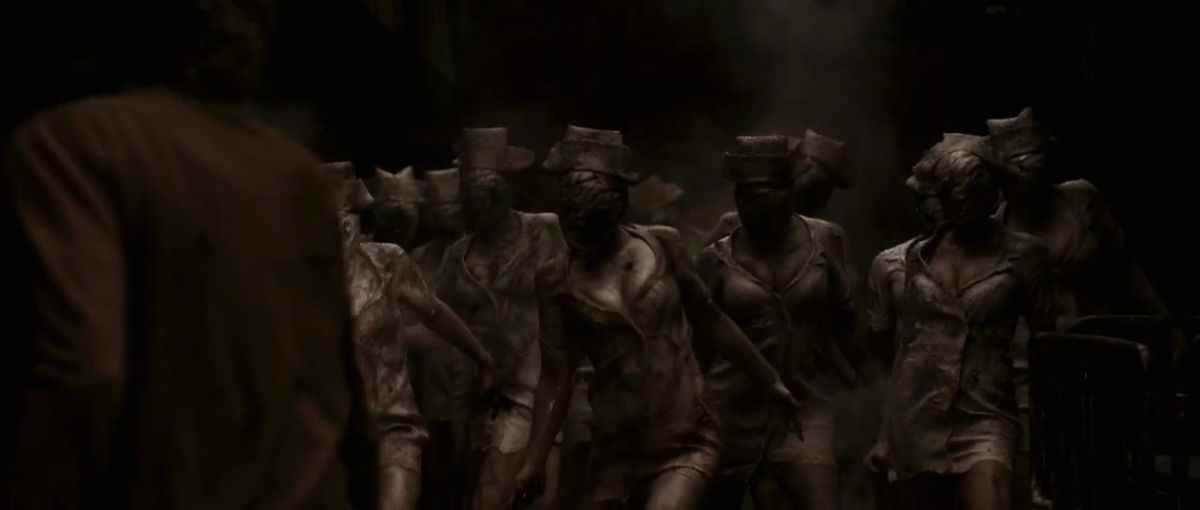 Plusieurs infirmières zombies sans visage se tiennent devant une femme blonde dans le film Silent Hill