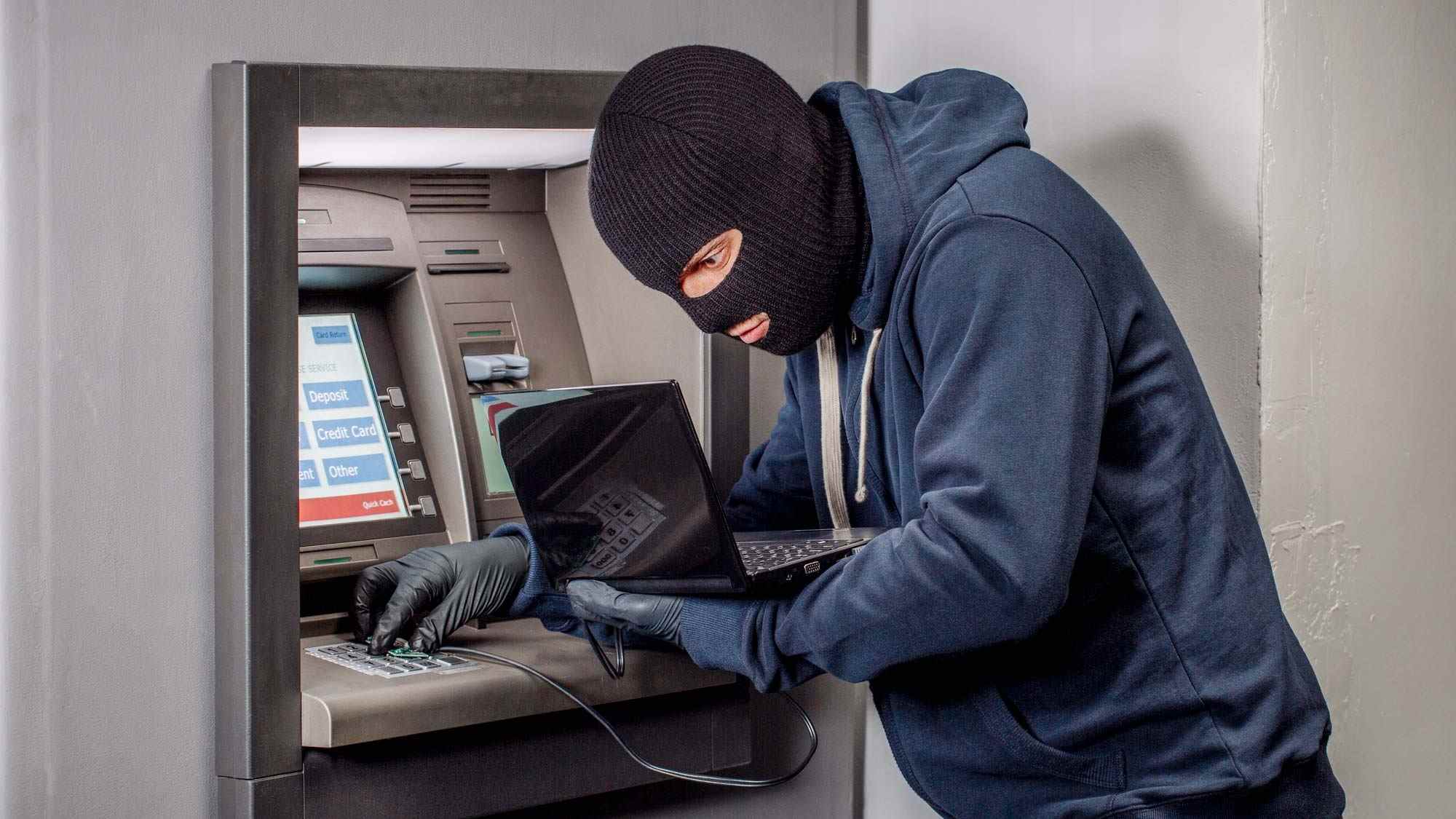 Un voleur installe un skimmer de carte de crédit sur un guichet automatique