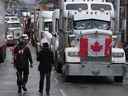 Les manifestants marchent entre les camions garés le long de la rue Wellington au centre-ville d'Ottawa alors que le 