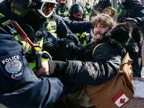 Un policier se débat avec un homme alors que les autorités s'efforcent de retirer la manifestation du Freedom Convoy au centre-ville d'Ottawa le 18 février 2022.