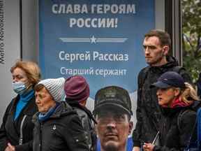 Sur cette photo d'archive, des piétons passent devant une affiche représentant un soldat russe avec un slogan indiquant 
