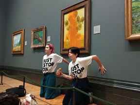 Une photo du groupe de campagne pour le climat Just Stop Oil montre des militants les mains collées au mur sous Vincent van Gogh "Tournesols" après avoir jeté de la soupe aux tomates sur le tableau à la National Gallery dans le centre de Londres le 14 octobre 2022.