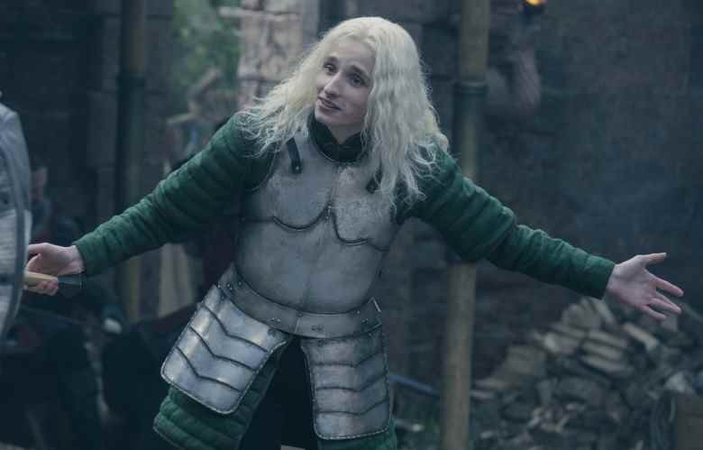Un homme adulte aux longs cheveux blonds blancs, portant une armure de combat médiévale;  encore de "Maison du Dragon."