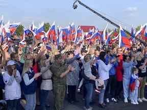 Les gens réagissent lors des célébrations marquant l'incorporation de la région de Donetsk à la Russie à Donetsk, en Ukraine, le vendredi 30 septembre 2022. La signature des traités faisant des quatre régions une partie de la Russie fait suite à l'achèvement du Kremlin-orchestré 
