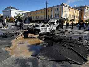 Des experts de la police examinent des voitures détruites dans le centre de Kyiv après plusieurs frappes russes le 10 octobre 2022.