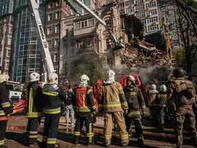 Des pompiers ukrainiens travaillent sur un bâtiment détruit après une attaque de drone à Kyiv le 17 octobre 2022, au milieu de l'invasion russe de l'Ukraine (Photo de YASUYOSHI CHIBA/AFP via Getty Images)