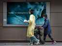 Un travailleur de la santé guide une femme portant un masque à l'extérieur de l'hôpital St. Michaels de Toronto pendant la pandémie de COVID-19. 