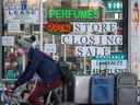Un cycliste portant un masque passe devant un panneau « Store Closing Sale » lors d'un voyage vers le nord sur l'avenue Spadina de Toronto. 