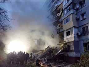 Des sauveteurs se rassemblent devant un immeuble résidentiel endommagé après une frappe à Zaporizhzhia, au milieu de l'invasion russe de l'Ukraine le 9 octobre 2022.