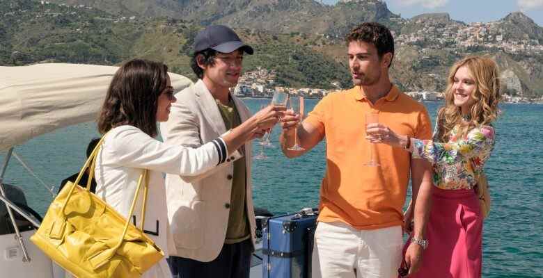 Two young heterosexual couples toast champagne on a dock in front of the sea and mountains; still from "The White Lotus" Season 2