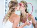 Femme embrassant le miroir dans la salle de bain avec coeur dessiné sur le miroir en rouge à lèvres