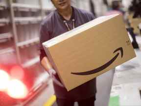 Un travailleur d'Amazon transporte une boîte dans une installation au Royaume-Uni