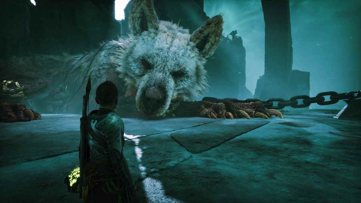 Atreus regarde un énorme loup endormi, qui semble être enchaîné à quelque chose avec des chaînes géantes, dans God of War Ragnarok.