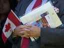 Un nouveau Canadien tient un drapeau canadien, son certificat de citoyenneté et une lettre signée par le premier ministre Justin Trudeau lors d'une cérémonie de citoyenneté en 2019.