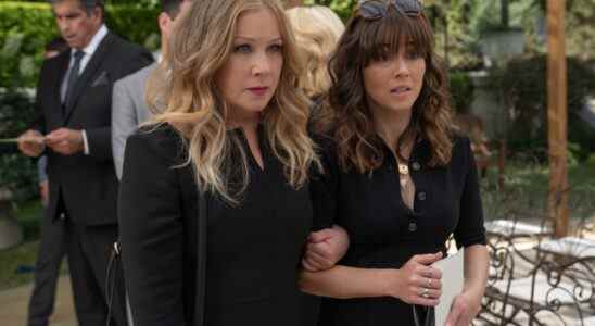 Two women in black funeral garb, looking stressed; one with her hand wrapped around the other's arm; still from "Dead to Me."