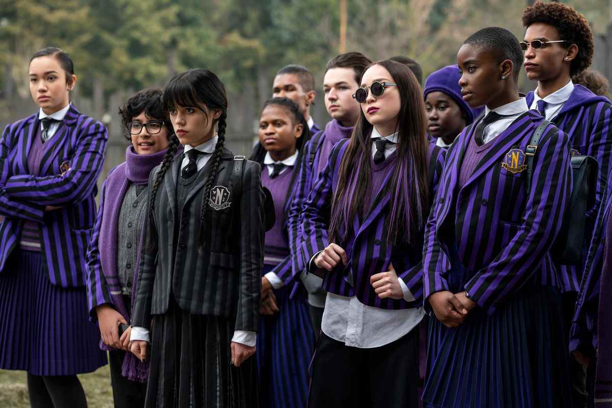 le mercredi se tient avec un groupe d'étudiants de l'académie Nevermore ;  ils portent tous des uniformes bleu foncé à fines rayures, sauf mercredi qui porte du noir