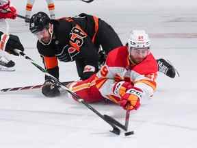 L'attaquant des Flames de Calgary Dillon Dube affronte l'attaquant des Flyers de Philadelphie Tanner Laczynski au Wells Fargo Center de Philadelphie le lundi 21 novembre 2022.