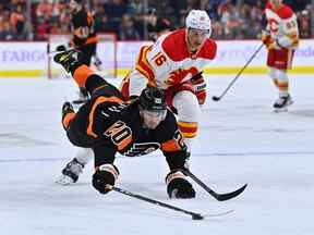 L'attaquant des Flyers de Philadelphie Kieffer Bellows plonge devant le défenseur des Flames de Calgary Nikita Zadorov au Wells Fargo Center de Philadelphie le lundi 21 novembre 2022.