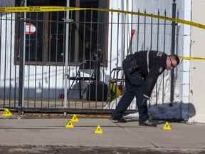 Un membre du Service de police d'Edmonton enquête sur les lieux d'une fusillade qui a fait un mort et six blessés dans un salon de la 118e avenue près de la 125e rue le 12 mars 2022.
