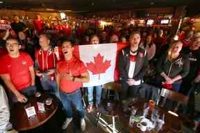 Les fans de football canadiens chantent l'hymne national avant le match alors que les fans se rassemblent au Ship & Anchor à Calgary le mercredi 23 novembre 2022 pour regarder le premier match de Coupe du monde du Canada au Qatar contre la Belgique.