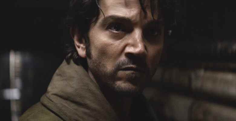 Shadowy close up on a man with dark hair, looking determined; still from "Andor."
