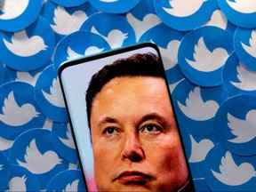 Une image d'Elon Musk est vue sur un smartphone placé sur des logos Twitter imprimés dans cette illustration.