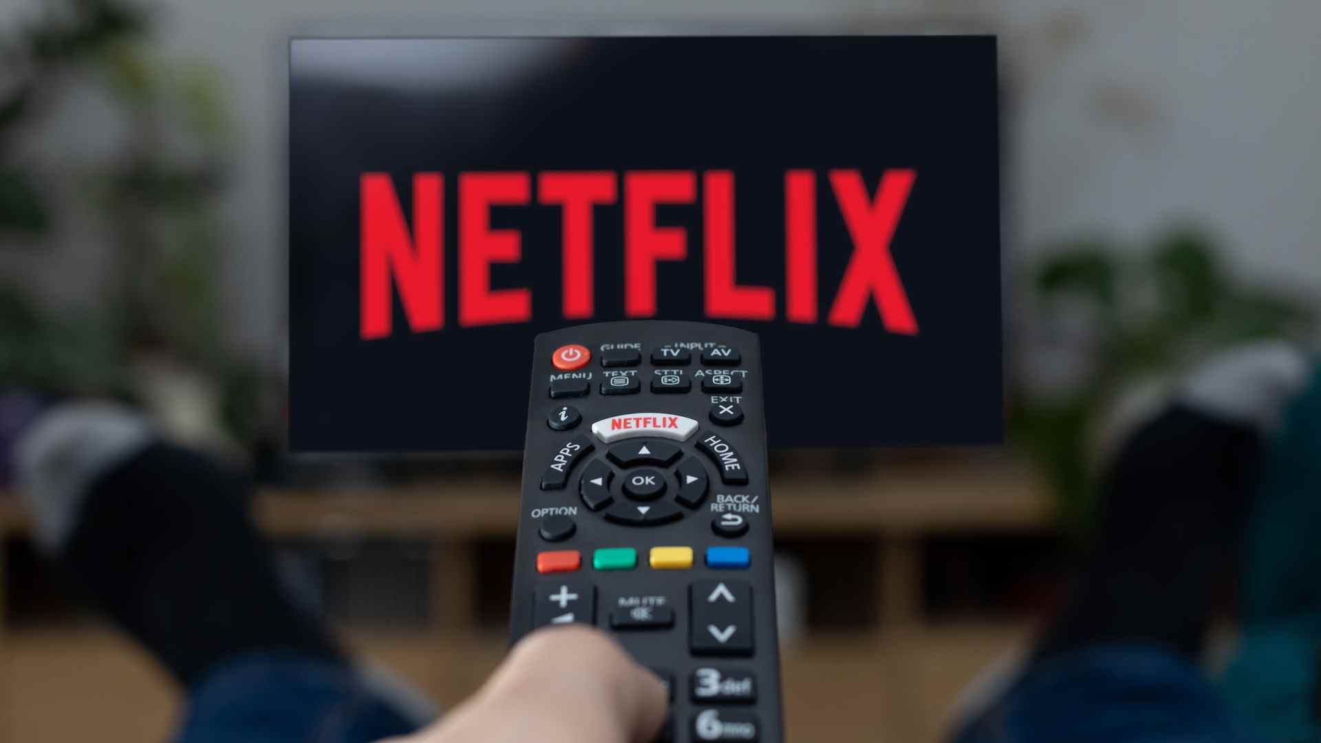 Une image promotionnelle d'une personne regardant Netflix sur son téléviseur, avec une télécommande dans la main gauche