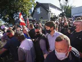 Le chef libéral Justin Trudeau est escorté par son détachement de sécurité de la GRC alors que les manifestants crient et lancent des pierres tout en quittant un arrêt de campagne dans une micro-brasserie locale pendant la campagne électorale fédérale à London, en Ontario, le 6 septembre 2021.